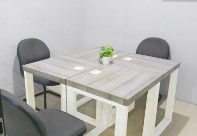 Small coworking table with grey chairs and a decorative plant.