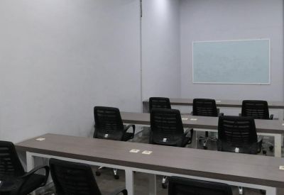 Long training table with black ergonomic chairs and a whiteboard.