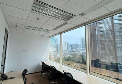 Bright open-plan workspace with long white desks and expansive city views.