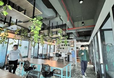 Open-plan coworking space with hanging plants and decorative flooring.