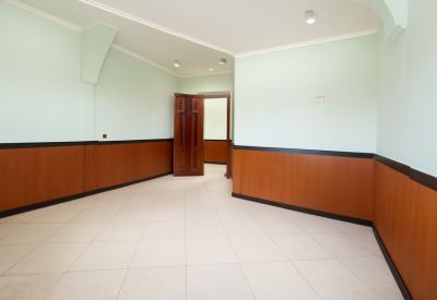 Empty multi-purpose room with tiled flooring and decorative wood paneling along the lower walls.