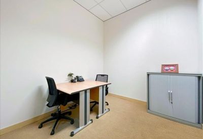Compact two-person office suite with a tan desk and black chairs.