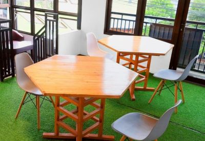 Indoor balcony area with green turf flooring and hexagonal wooden tables.