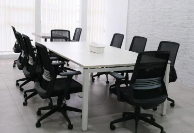 Meeting room with white rectangular table and ergonomic mesh chairs.