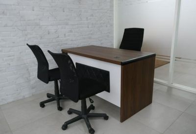Private office workstation with a wooden desk and two guest chairs.