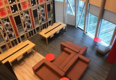 Spacious communal lounge with red sofas and high ceilings viewed from above.