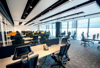 Large open-plan office with numerous workstations and floor-to-ceiling windows.
