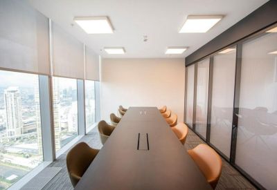 Modern conference room with a long dark table and tan chairs against city views.