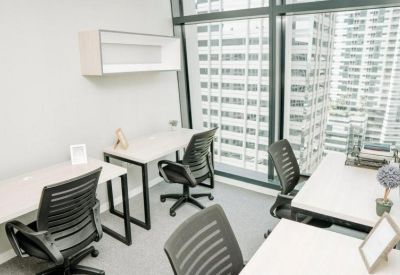 Bright shared office with white desks and ergonomic black chairs.