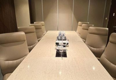 Professional boardroom with a long cream table and tan leather chairs.