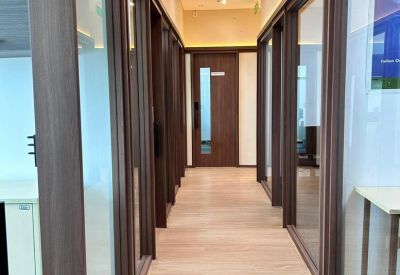 A modern hallway with wooden door frames and glass partitions under recessed lighting.