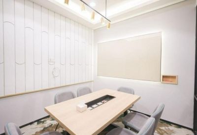 Bright meeting room with a light wood table, grey chairs, and a white paneled feature wall.