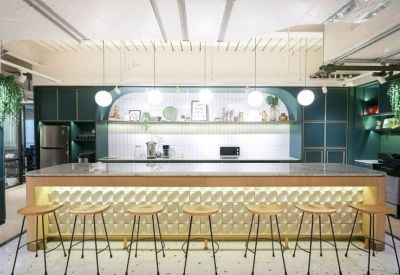 Wide-angle view of a long cafe bar with glowing decorative panels and wooden stools.
