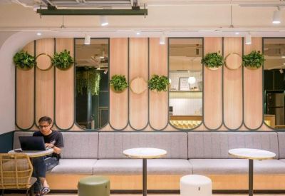Cozy lounge area featuring a long grey bench, wooden wall panels, and several potted plants.