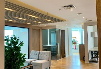 Modern lobby area with wood flooring, grey armchairs, and indoor plant.