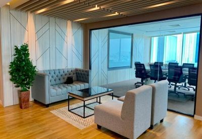 Lounge area with a tufted grey sofa, coffee table, and glass-walled meeting room.