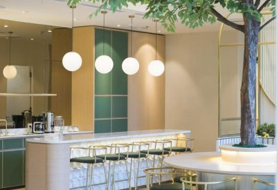 Cafe-style breakout area with a marble-topped bar, high stools, and a decorative indoor tree.
