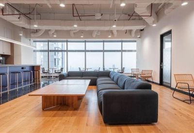 Modern lounge area with a long dark grey sofa, wooden flooring, and a breakfast bar.