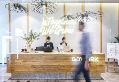 Branded wooden reception desk with greenery and a neon sign reading Together We Grow.