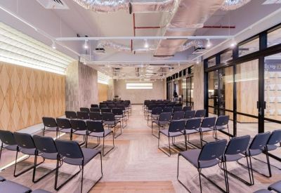 Professional meeting room set up with rows of grey chairs and a glass partition wall.