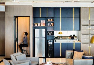 Modern office pantry area with blue cabinetry, a refrigerator, and a small private phone booth.