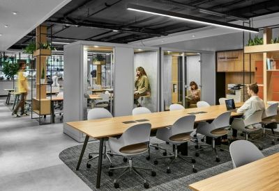Modern workspace featuring private acoustic phone booths and a long wooden communal desk.