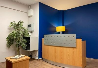 Reception area featuring a wooden desk, vibrant blue feature wall, and a yellow lamp.