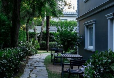 Stone paved garden path running alongside a grey office building with outdoor seating.