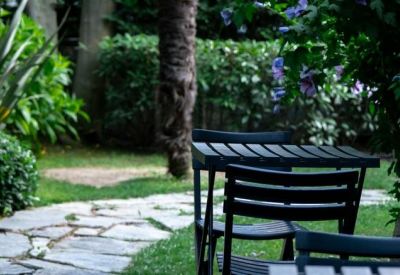 Lush garden breakout area with a dark wooden table and chairs beside a stone path.