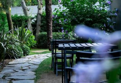 Garden seating area with a stone walkway and purple flowering bushes in the background.