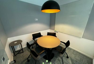 A modern meeting room featuring a round table and a black dome pendant light with a gold interior.