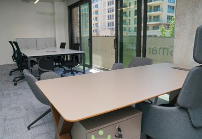 Bright workspace featuring light wood desks and large sliding glass doors leading to a balcony.