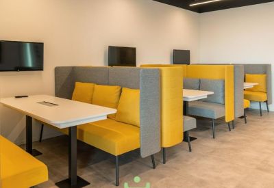 Private breakout booths with yellow cushions, grey dividers, and integrated wall-mounted screens.