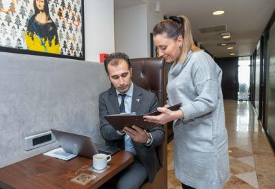 Two colleagues reviewing a document at a small table next to a coffee cup and laptop.