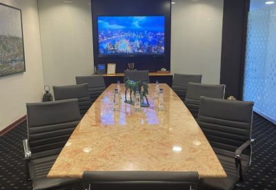 Professional boardroom featuring a large marble-top table, leather chairs, and a wall-mounted TV.