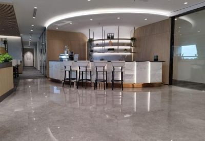 Sleek modern cafe and bar area with marble flooring and curved overhead lighting.