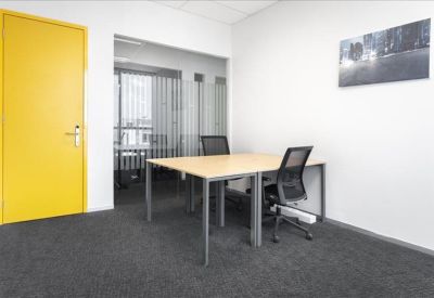 Bright private office featuring a yellow door and a two-person wooden desk.