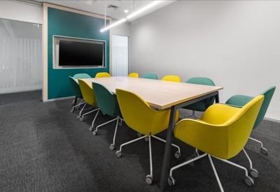 Professional meeting room with a large screen and colorful yellow and teal chairs.