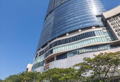 Exterior view of the soaring glass-facade Pakuwon Centre skyscraper against a clear blue sky.