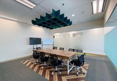 Meeting room with a long wooden table, black ergonomic chairs, and a creative acoustic ceiling fixture.
