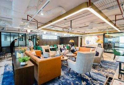 Bright breakout space with plush armchairs and views of a glass-walled office area.