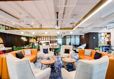 Large shared lounge featuring orange sofas, velvet armchairs, and colorful patterned rugs.