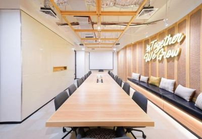 Long communal boardroom table under a decorative wooden ceiling with Together We Grow neon signage.