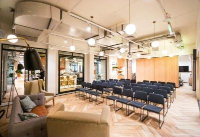 Large meeting room with rows of blue chairs, a chevron wood floor, and globe pendant lighting.