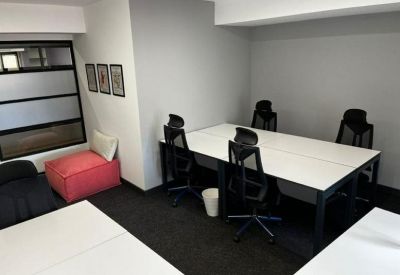 Communal breakout area with a pink beanbag and white workstations.