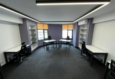 Bright coworking space with peripheral desks and purple accent walls.