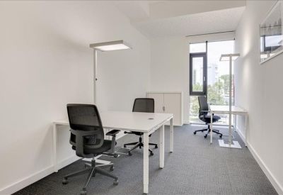 Bright three-person office suite with white desks and black ergonomic chairs.