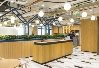 Reception desk with light wood paneling, a planter box, and geometric blue overhead framing.