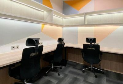 L-shaped coworking desk area with ergonomic chairs and colorful geometric wall patterns.