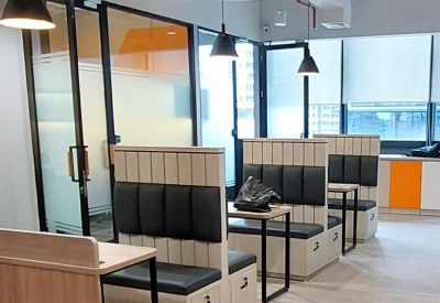 Row of semi-private booth pods with black padded backs and light wood tables.